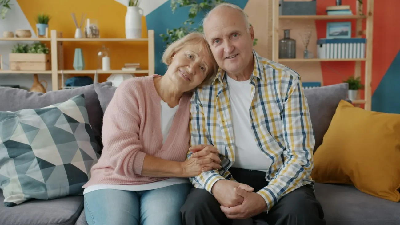 Pareja de propietarios sonriendo en el sofá de su casa
